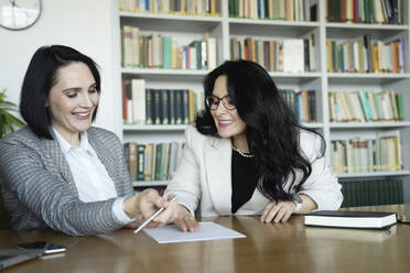 Glückliche Geschäftsfrauen planen ihre Strategie in einer Besprechung am Schreibtisch - NJAF00291