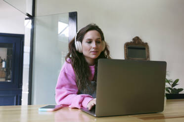 Junger Freiberufler arbeitet am Laptop in einem Café - SYEF00300