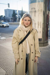 Junge Frau im Mantel auf dem Fußweg stehend - JJF00633