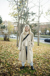 Young woman with hand in pocket standing at park in autumn - JJF00637