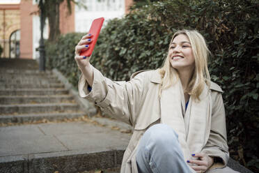 Beautiful woman taking selfie through smart phone sitting on steps - JJF00658