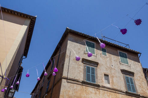 Italy, Lazio, Tuscania, Bell-shaped festival decorations hanging in front of house - MAMF02664