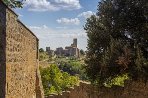 Italy, Lazio, Tuscania, View of Chiesa di San Pietro church in summer with walls in foreground - MAMF02678