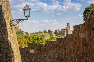 Italy, Lazio, Tuscania, View of Chiesa di San Pietro church in summer with walls in foreground - MAMF02680