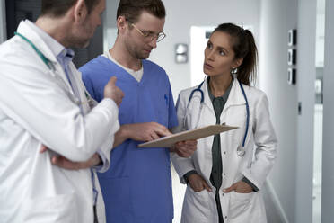 Arzt bespricht sich mit Kollegen über die Krankenakte in der Klinik - ABIF01861