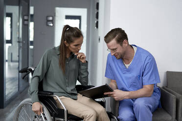 Doctor discussing with patient sitting in wheelchair - ABIF01866