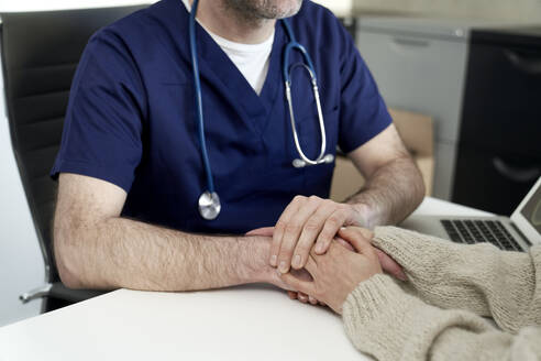 Arzt hält Hände und tröstet Patienten in der Klinik - ABIF01881