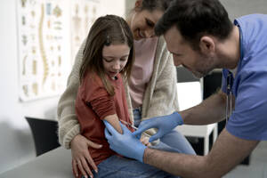 Arzt injiziert in der Klinik eine Spritze in den Arm eines Mädchens - ABIF01887