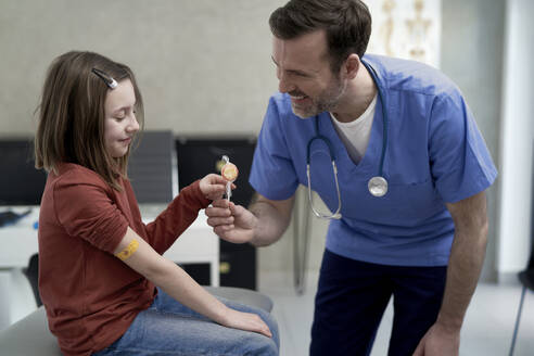 Glücklich reifen Arzt geben Lutscher zu Mädchen in der Klinik - ABIF01890