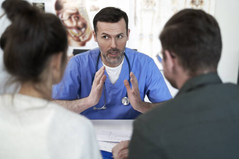Arzt erklärt und diskutiert mit einem Paar in der Klinik - ABIF01897