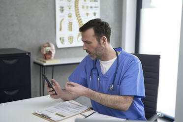 Arzt spricht per Videoanruf über ein Smartphone in einer Klinik - ABIF01906