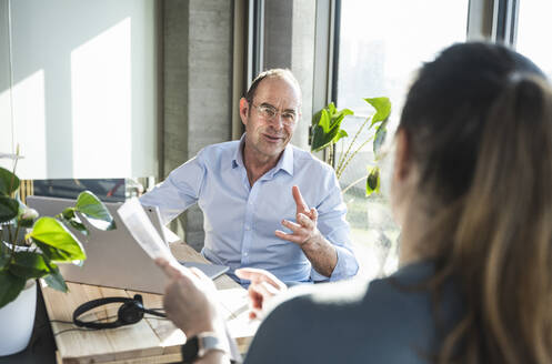 Mature businessman discussing with colleague in office - UUF28501