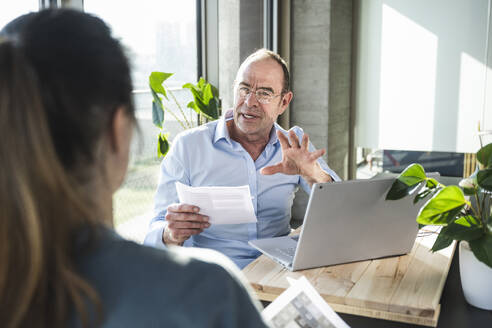 Reifer Geschäftsmann erklärt einem Kollegen im Büro die Strategie - UUF28509