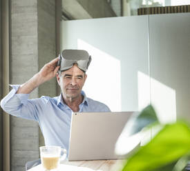 Businessman with VR glasses using laptop in office - UUF28513