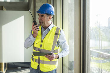 Ingenieur mit Walkie-Talkie und Tablet-PC im Büro - UUF28520