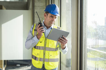 Ingenieur mit Walkie-Talkie und Tablet-PC im Büro - UUF28521