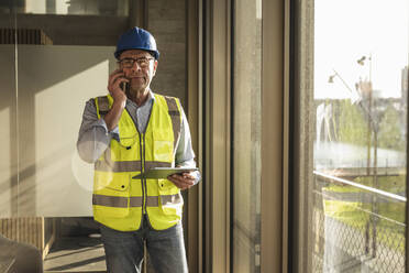 Ingenieur mit Smartphone und Tablet-PC im Büro - UUF28524