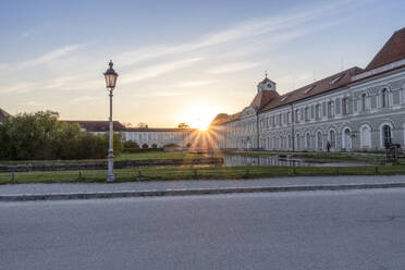 Deutschland, Bayern, München, Sonnenuntergang über Schloss Nymphenburg mit leerer Straße im Vordergrund - MAMF02697