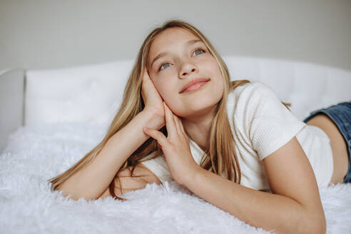 Smiling girl day dreaming lying on bed at home - MDOF00858