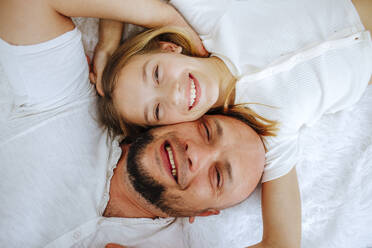 Glücklicher Vater und Tochter liegen zu Hause auf dem Bett - MDOF00865