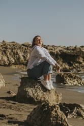 Frau sitzt auf einem Felsen am Strand - DMGF01086