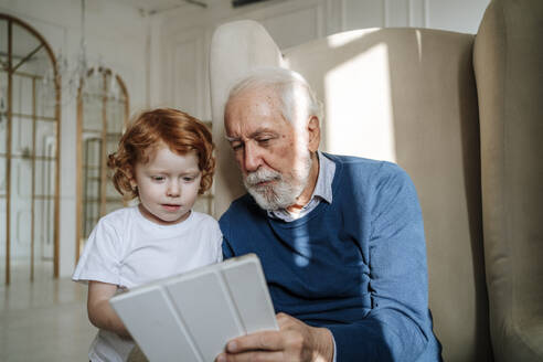 Älterer Mann teilt Tablet-PC mit Enkel zu Hause - MDOF00876