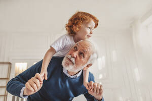 Grandfather giving piggyback ride to grandson at home - MDOF00887