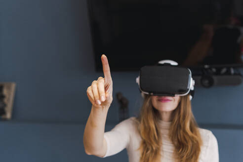 Frau mit Virtual-Reality-Headset gestikuliert zu Hause - PNAF05080