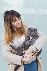 Smiling woman carrying gray cat - PNAF05092