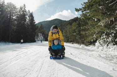 Father and son sledding in winter landscape - ALKF00192