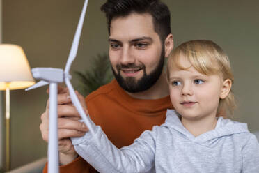 Smiling father teaching about wind turbine to son at home - AAZF00162