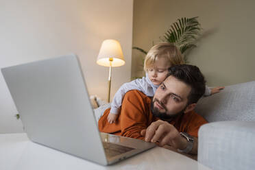 Man using laptop with son at home - AAZF00166