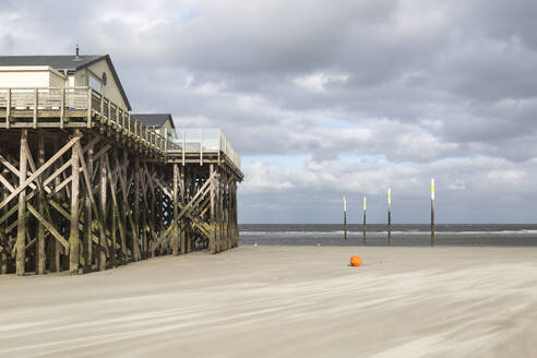 Deutschland, Schleswig-Holstein, St. Peter-Ording, Bewölkter Himmel über Stelzenhäusern am Sandstrand - ASCF01741