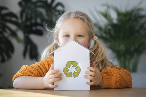 Blondes Mädchen hält Hausmodell mit Recycling-Logo - AAZF00183
