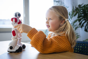 Mädchen berührt Roboter auf Tisch zu Hause - AAZF00187