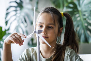 Girl looking at wind turbine model at home - AAZF00218