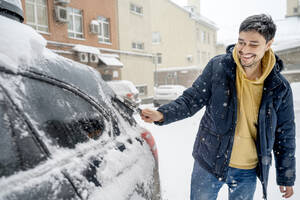 Glücklicher Mann entfernt Schnee mit Bürste vom Auto - ANAF01092
