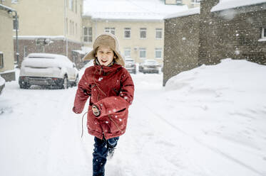 Boy wearing fur hat running in snow - ANAF01096