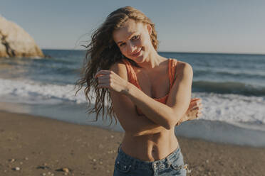 Smiling woman standing at beach on sunny day - DMGF01098