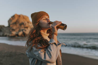 Woman drinking beer at beach - DMGF01107