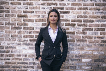 Selbstbewusste Geschäftsfrau vor einer Backsteinmauer stehend - AMWF01278