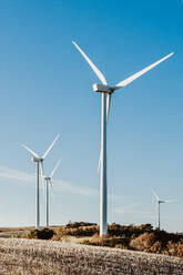 Weiße hohe ind Turbine für alternative Energieerzeugung gegen wolkenlosen blauen Himmel in Feld auf dem Lande - ADSF43480