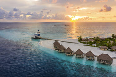 Luftaufnahme eines Leuchtturms eines Luxusresorts mit Bungalows auf einer kleinen Insel bei Sonnenuntergang, Laccadive Sea, Indischer Ozean, Malediven-Archipel. - AAEF17528