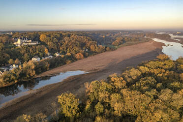 Luftaufnahme von Häusern entlang der Loire mit Sandbänken bei Sonnenuntergang in Gennes, Maine-et-Loire, Frankreich. - AAEF17672