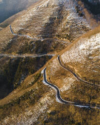 Aerial view of a scenic forest road on mountainside in wintertime with snow on Mount Terminio, Serino, Avellino, Irpinia, Campania, Italy. - AAEF17698