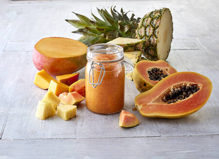 Halbierte Mangofrüchte, Papaya, Ananas und Smoothie im Glas - KSWF02336