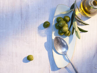 Löffel, rohe Oliven und Karaffe mit Olivenöl - KSWF02341