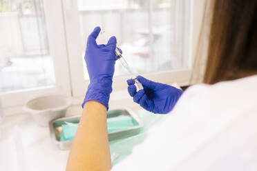 Hände eines Arztes bei der Vorbereitung einer Impfstoffspritze im Krankenhaus - MMPF00685