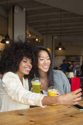 Eine bunt gemischte Gruppe von Freunden hält einen Moment mit einem Selfie und Getränken in einem örtlichen Café fest - MMPF00691