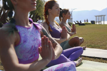 Woman with eyes closed meditating with friends at park - SYEF00331